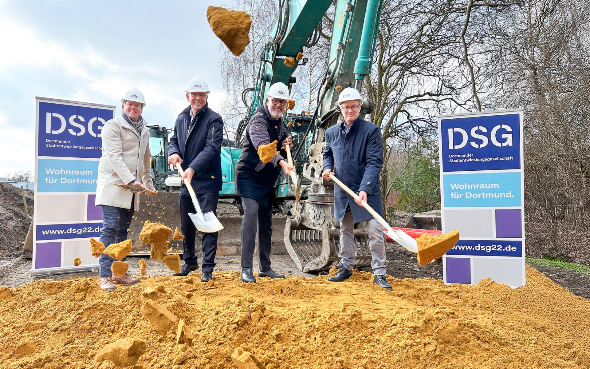 Grundsteinlegung für Wohnprojekt in Dortmund: Vier Personen heben mit Schaufeln den Boden.