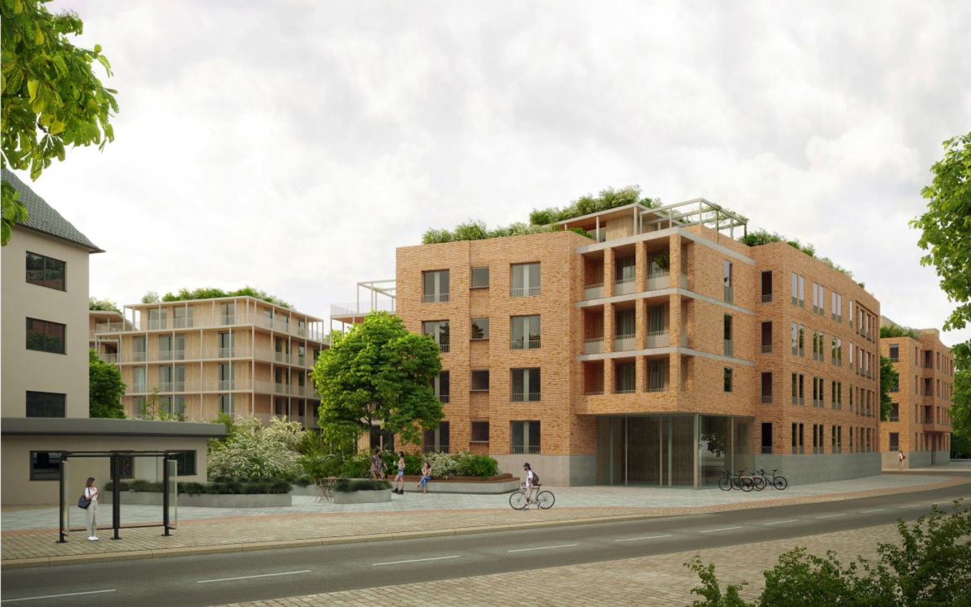 Moderne Wohnanlage mit Backsteinfassade, umgeben von Bäumen und Fahrrädern. Heller Himmel.